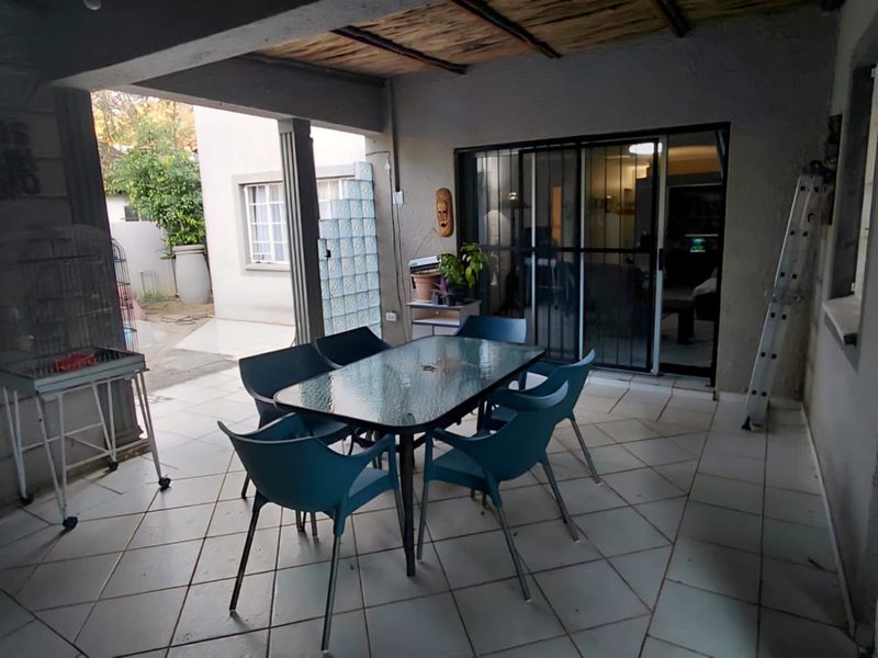 A covered outdoor patio area featuring tiled flooring, a glass block feature wall, and sliding door access to the main interior living space.