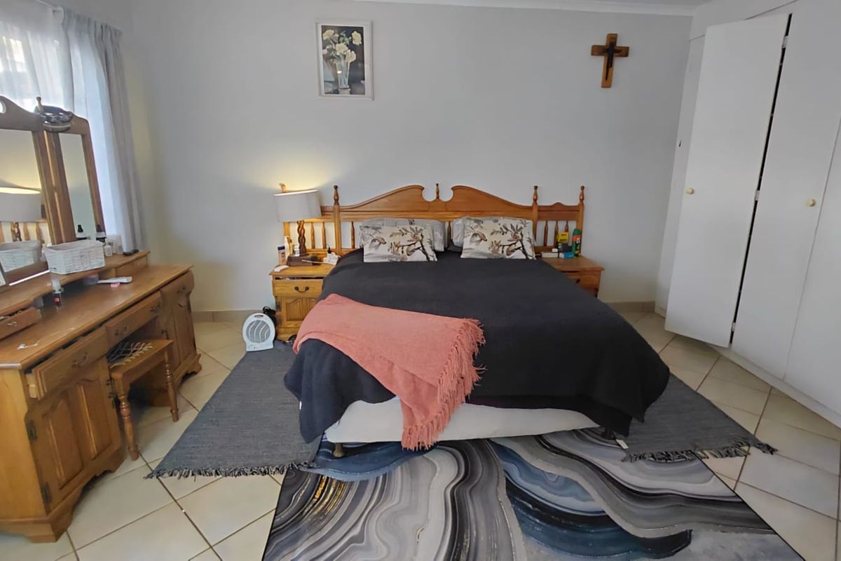 A well-lit bedroom featuring tiled flooring and built-in cupboards, providing a functional and comfortable living space.