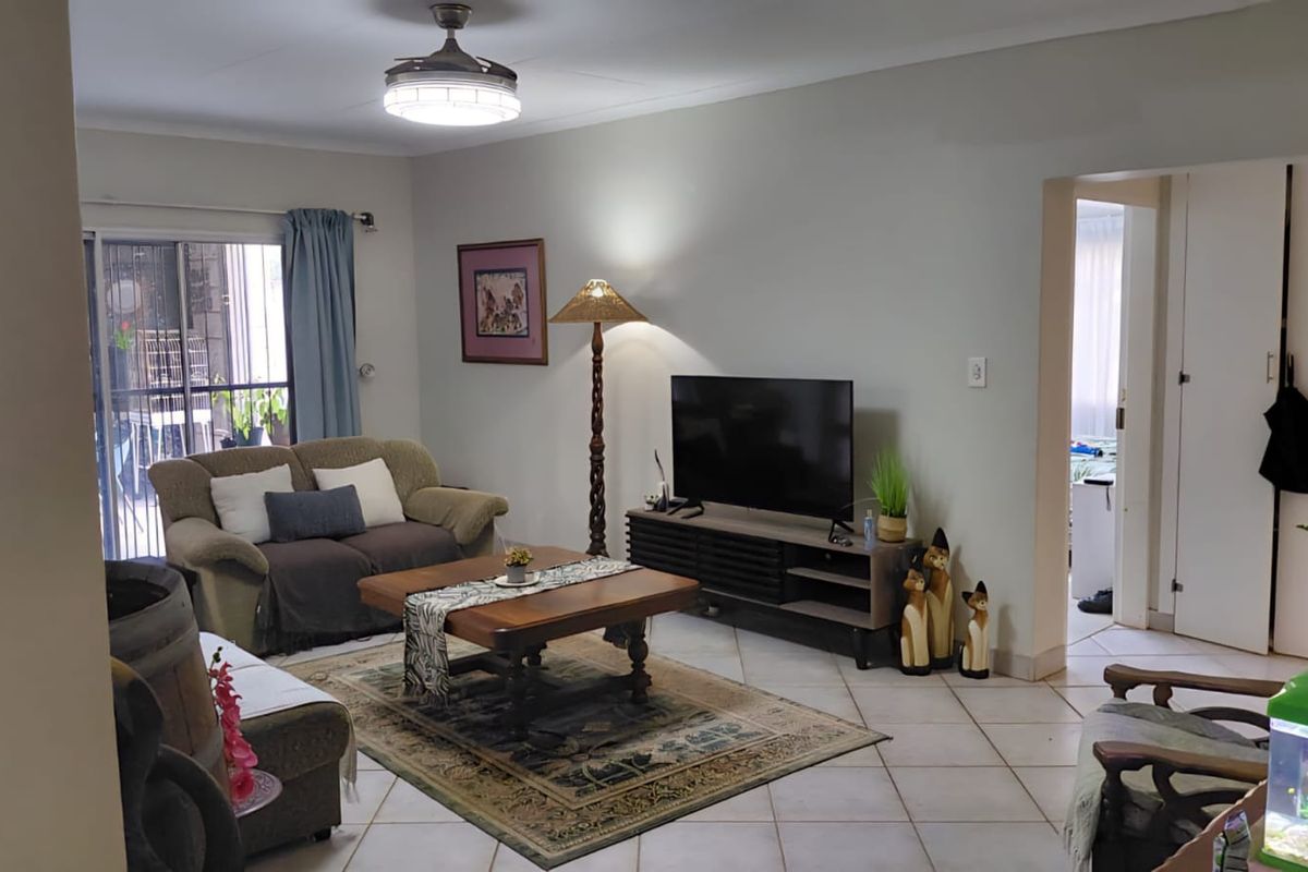 A comfortable living room featuring tiled flooring, a ceiling fan, and a sliding glass door providing access to the exterior.