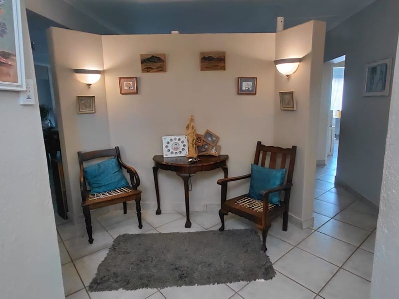 An entry area featuring tiled flooring, a central partition wall with integrated wall sconce lighting, and access to adjacent living spaces.
