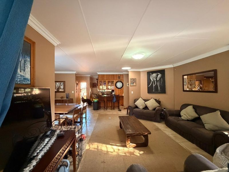 Spacious open-plan living and dining area featuring tiled flooring, crown molding, and a built-in bar, offering a versatile layout for family living.