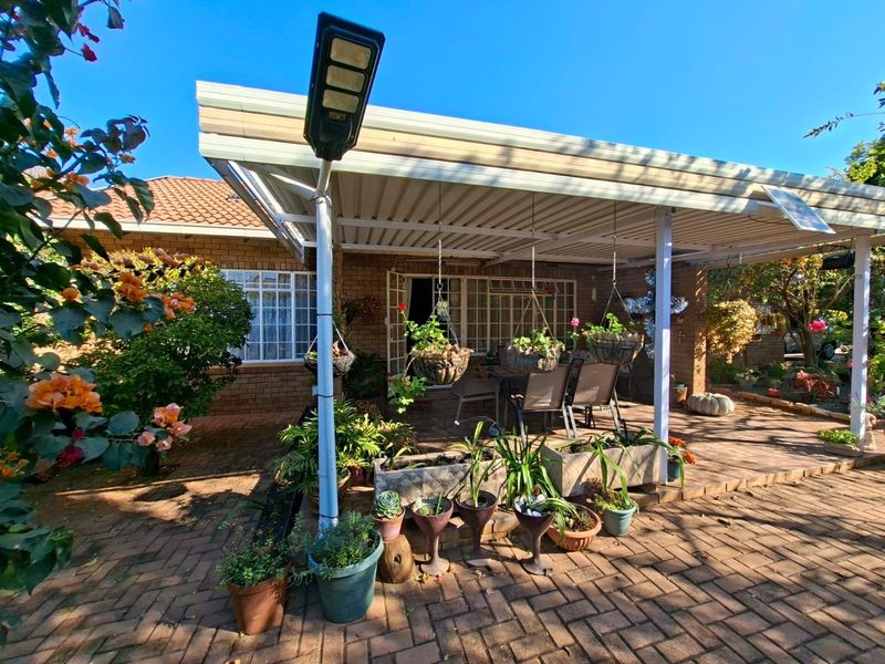 A covered brick-paved patio area featuring a brick facade, security gate access, and an integrated solar floodlight, providing a functional outdoor entertainment space.