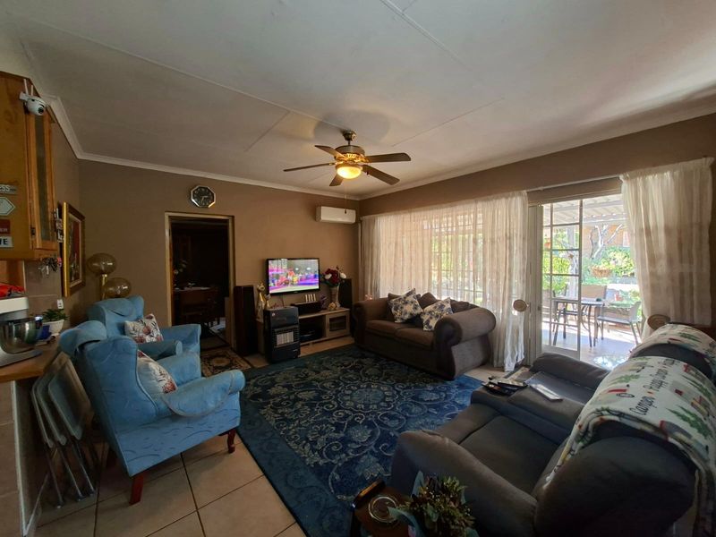 A comfortable living room featuring tiled floors, a ceiling fan, split-system air conditioning, and direct access to an outdoor patio area.