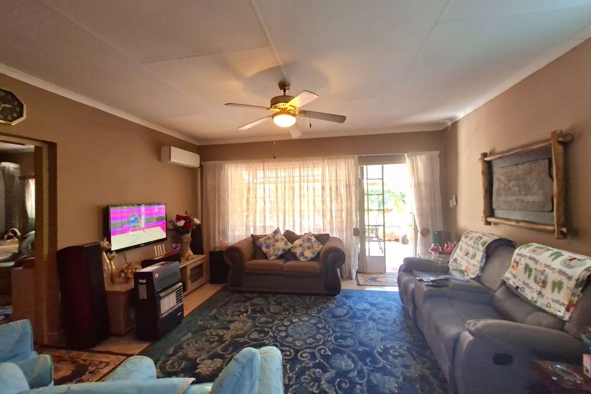 A comfortable living room featuring a ceiling fan, wall-mounted air conditioning unit, and direct access to the outdoor area through a sliding glass door.
