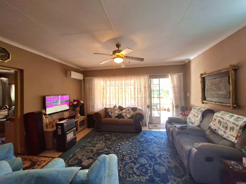 A comfortable living room featuring a ceiling fan, wall-mounted air conditioning unit, and direct access to the outdoor area through a sliding glass door.