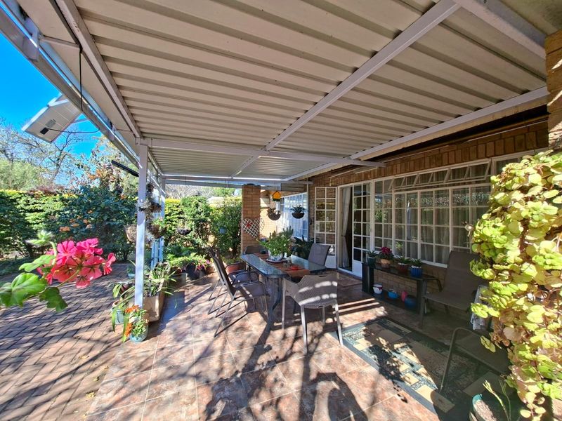 A covered outdoor patio area featuring tiled flooring, a corrugated metal roof, and direct access to the home through sliding glass doors.