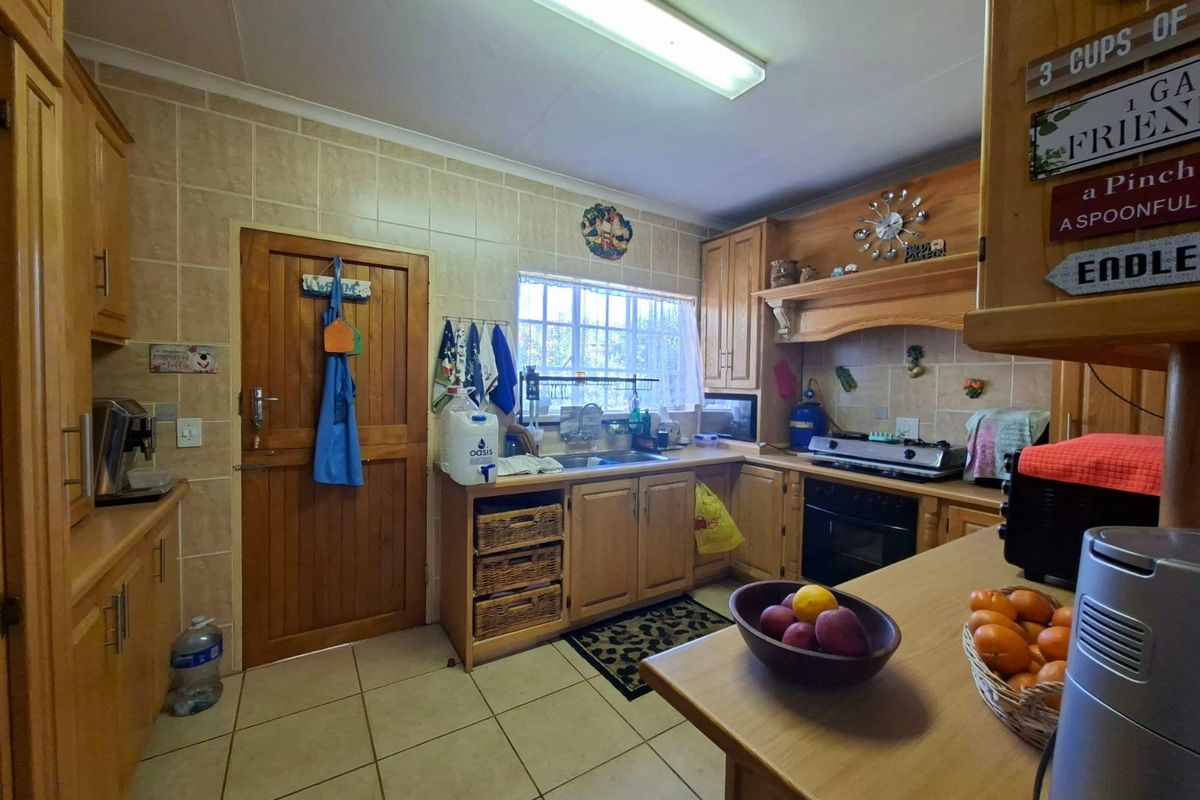 A functional kitchen featuring wooden cabinetry, tiled backsplash, built-in oven, and hob, offering a traditional layout with ample storage space.
