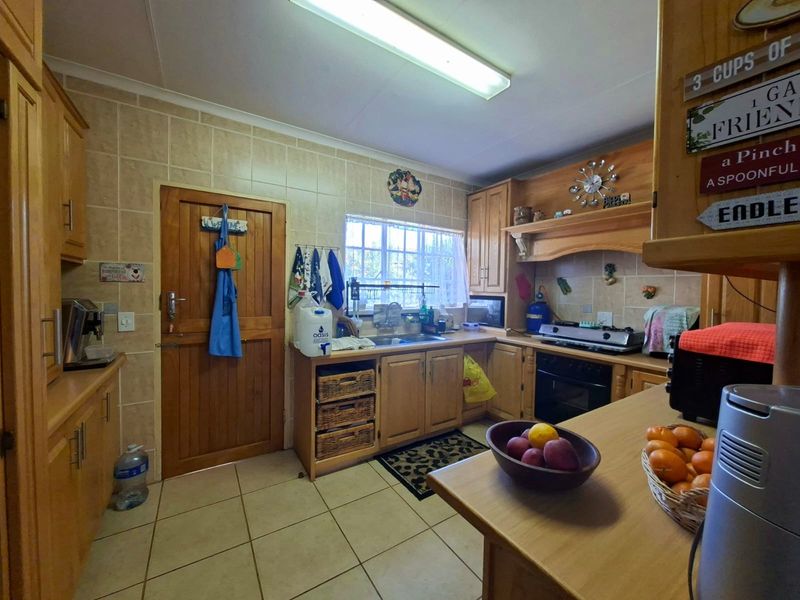 A functional kitchen featuring wooden cabinetry, tiled backsplash, built-in oven, and hob, offering a traditional layout with ample storage space.