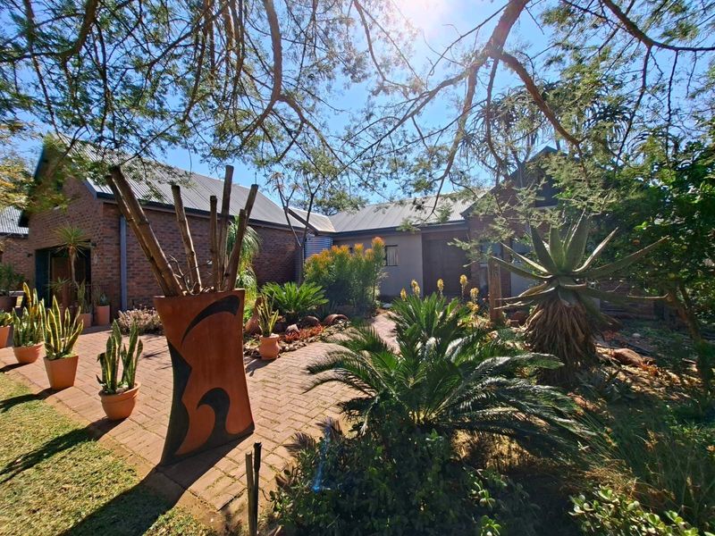 A well-maintained rear courtyard featuring brick exterior walls, a metal roof, and established garden landscaping.