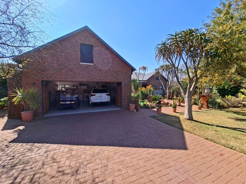 A well-maintained brick garage with a paved driveway and established garden, featuring a spacious interior suitable for vehicle storage.
