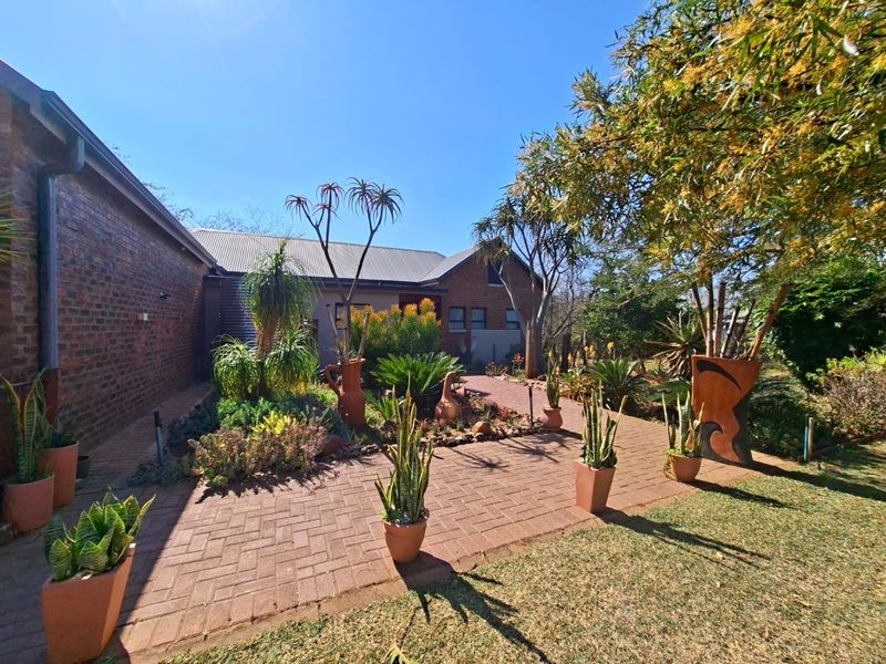 A well-maintained rear garden area featuring extensive brick paving, established landscaping, and a classic face brick exterior wall.