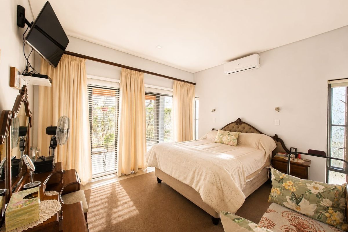 A well-lit bedroom featuring a split-system air conditioner, neutral carpeting, and sliding glass doors that provide access to the outdoor area.