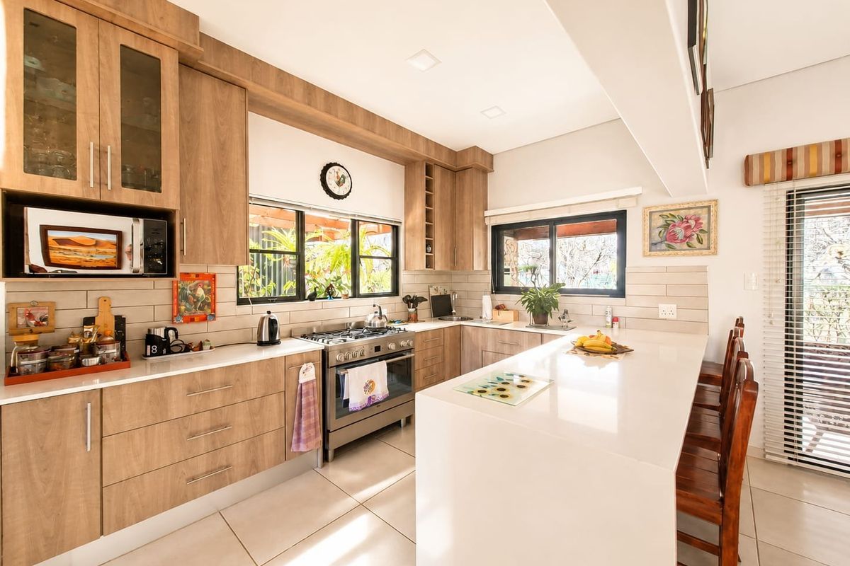 Modern kitchen featuring wood-finish cabinetry, stone countertops, a central island, and a built-in gas stove with oven, complemented by tiled flooring and recessed lighting.