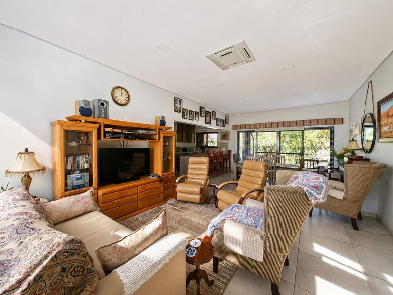 Spacious open-plan living and dining area featuring tiled floors, recessed lighting, ducted air conditioning, and large sliding glass doors leading to the outdoors.