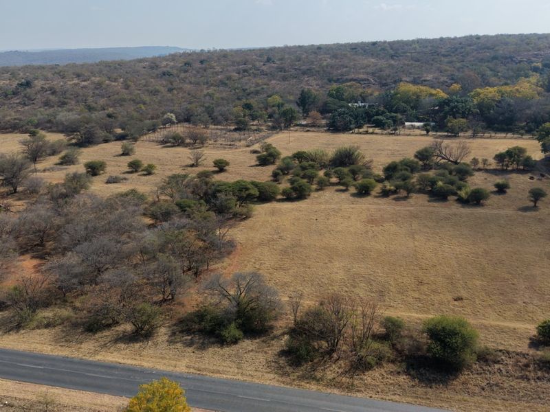 An aerial view of the expansive farm property, showcasing the open landscape, natural vegetation, and adjacent paved road access.