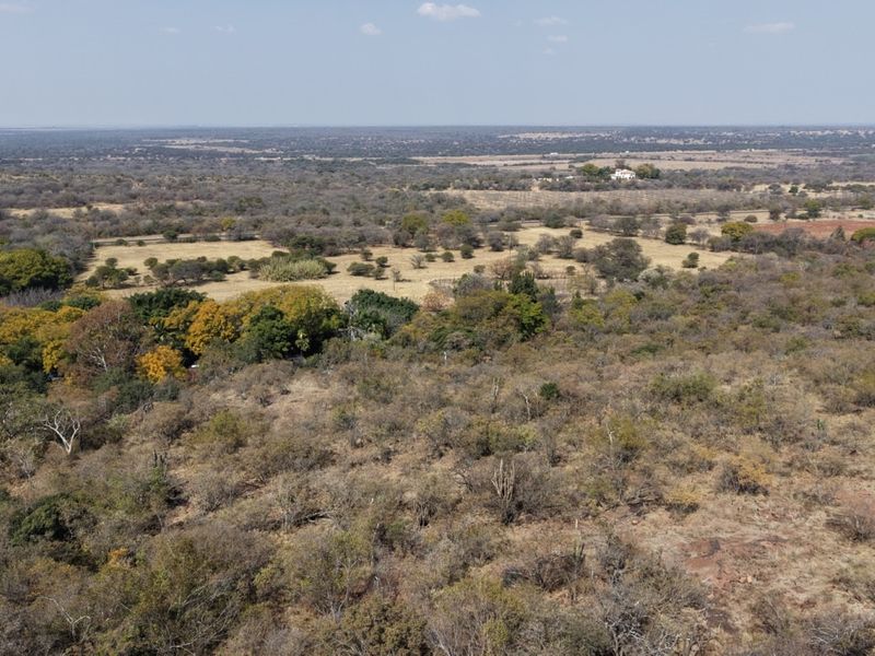 An expansive aerial view of the rural farm landscape, showcasing the natural terrain, vegetation, and surrounding countryside.