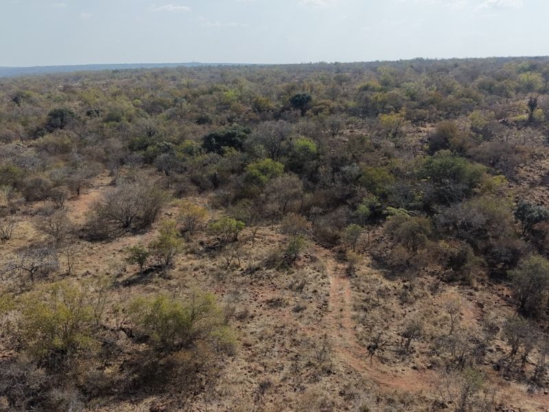 An aerial view of the expansive farm landscape featuring natural bushveld vegetation and an existing dirt track.