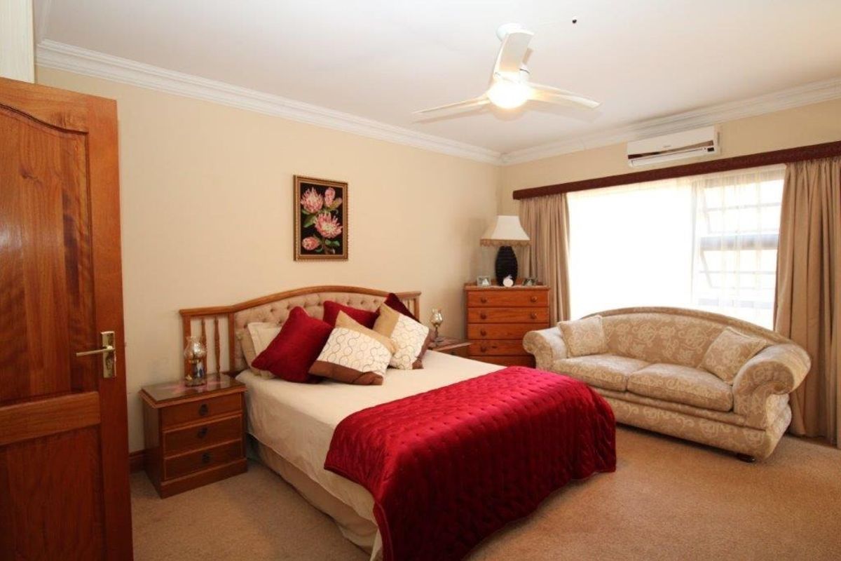 A carpeted bedroom featuring a ceiling fan, split-system air conditioning, and classic timber door finishes.