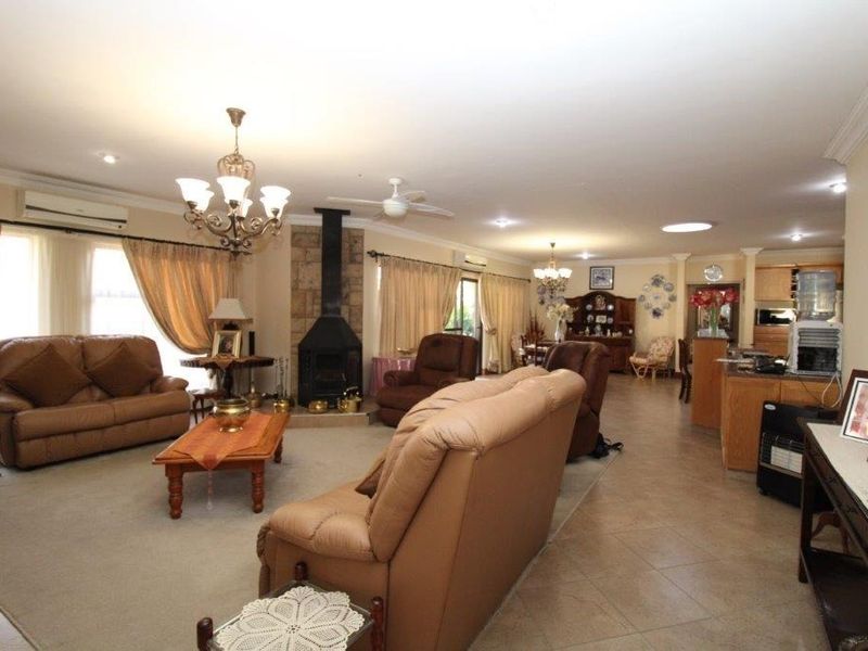 Spacious open-plan living area featuring a stone-clad fireplace, split system air conditioning, and a combination of tiled and carpeted flooring.