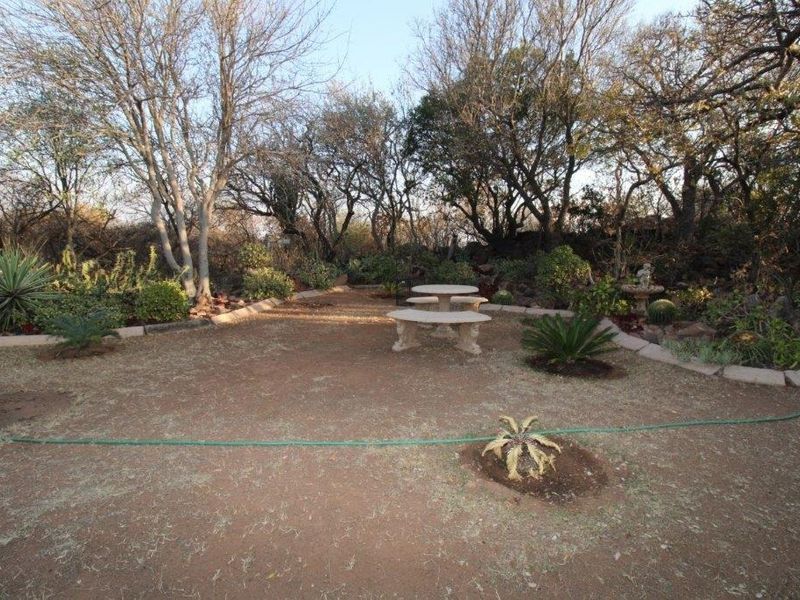 A spacious, established garden area featuring mature trees, stone garden edging, and natural landscaping, offering a quiet outdoor space.