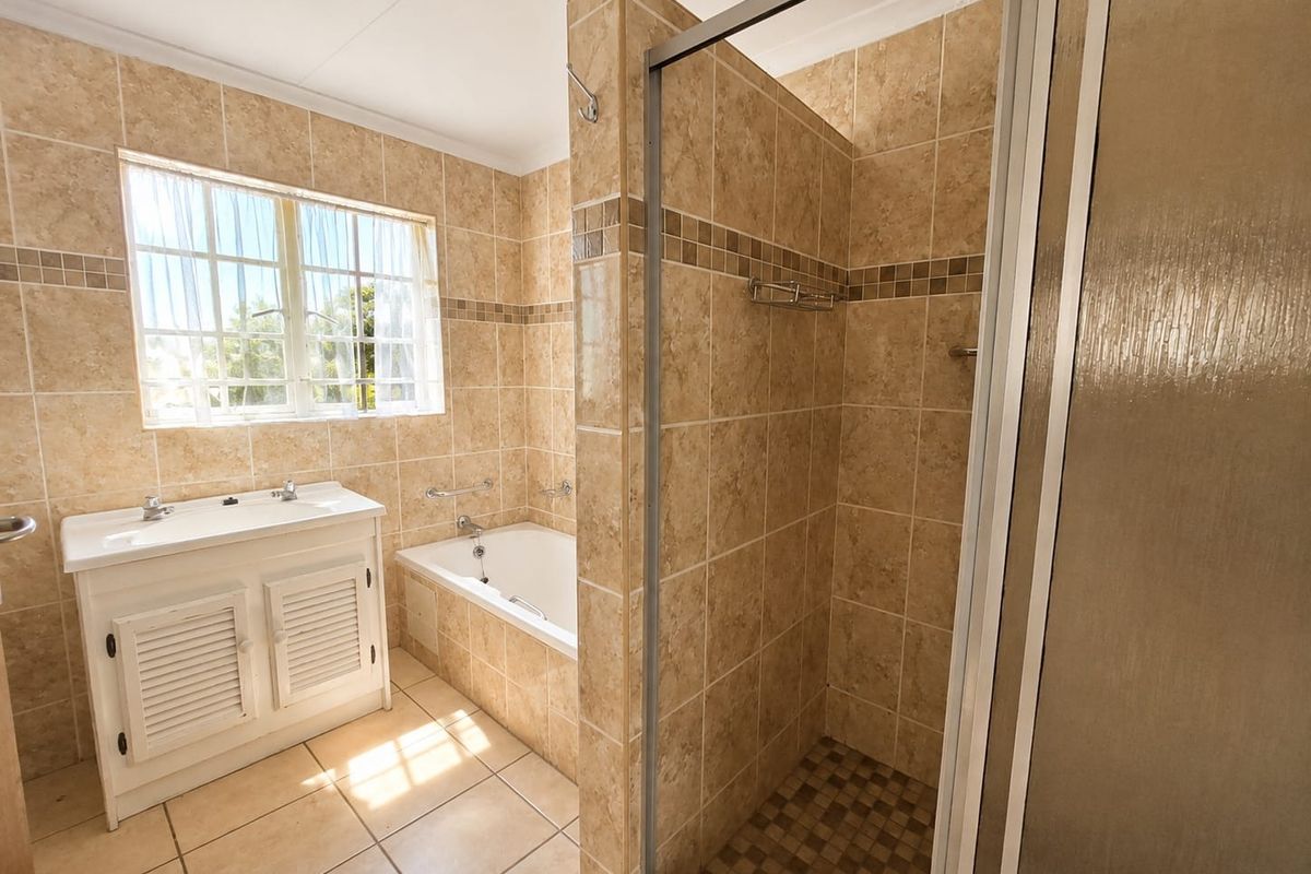 A functional bathroom featuring a built-in vanity, a tiled shower enclosure, and a bathtub with neutral ceramic wall and floor tiling.