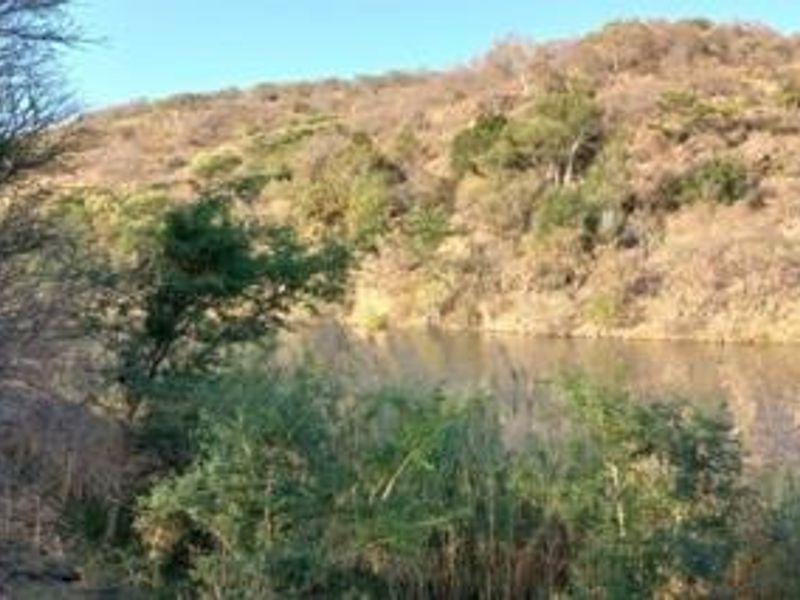 A scenic view of a natural water feature set against a sloped, vegetated hillside on the residential land.