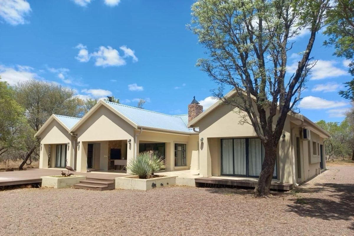 Rear view of the house featuring a covered patio with built-in braai, sliding glass doors, and a spacious deck area.