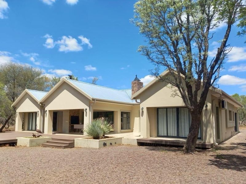 Rear view of the house featuring a covered patio with built-in braai, sliding glass doors, and a spacious deck area.