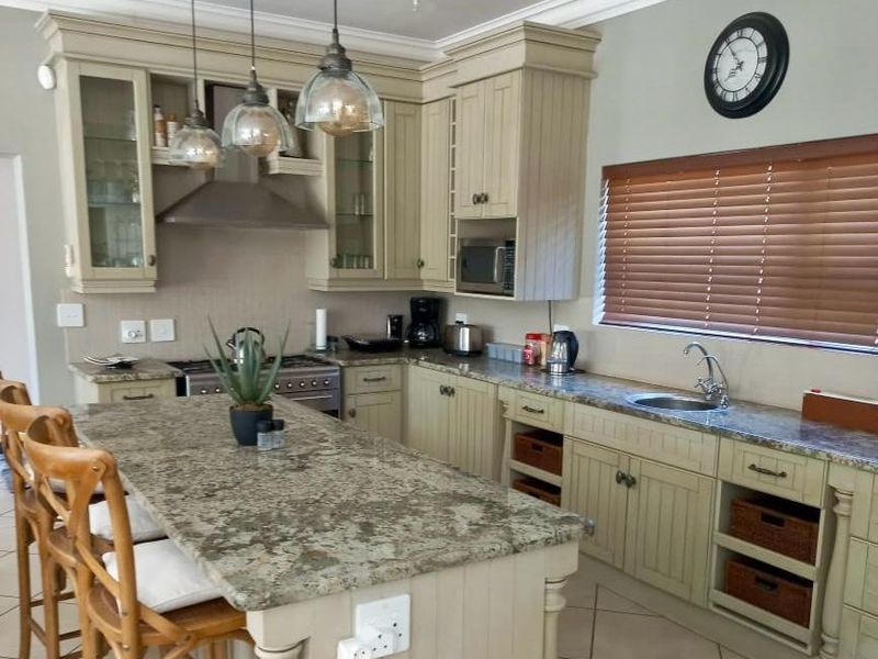 A well-appointed kitchen featuring granite countertops, a central island, built-in cabinetry, and integrated appliances, finished with crown molding and recessed lighting.