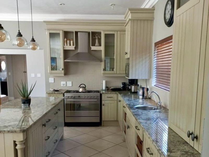 A well-appointed kitchen featuring granite countertops, stainless steel appliances, custom cabinetry, and elegant pendant lighting, offering a functional and stylish culinary space.
