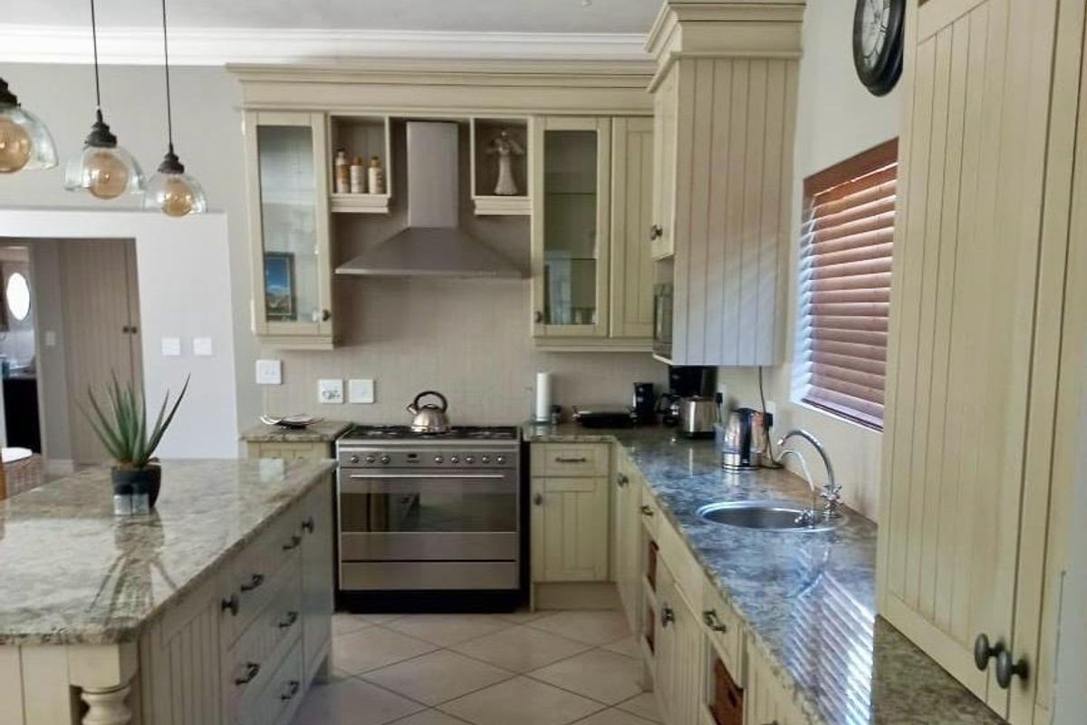 A well-appointed kitchen featuring granite countertops, stainless steel appliances, custom cabinetry, and elegant pendant lighting, offering a functional and stylish culinary space.