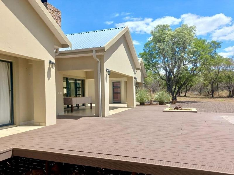 Spacious covered patio featuring composite decking, stone chimney detail, and direct access to the home through large sliding glass doors.