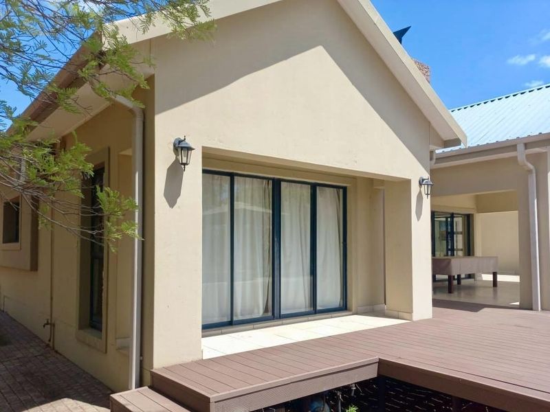 Rear exterior view featuring a composite deck, tiled patio area, and sliding glass doors leading into the home.