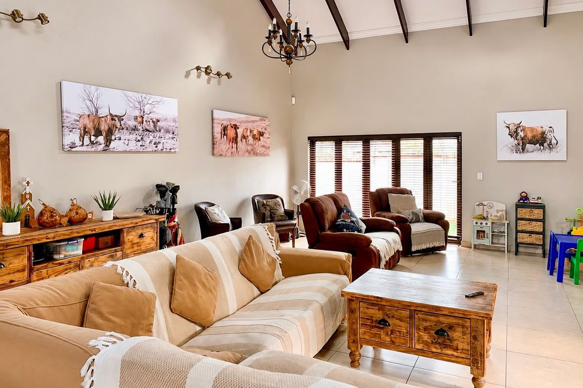 Spacious living room featuring high vaulted ceilings with exposed timber beams, tiled flooring, and large windows fitted with venetian blinds.