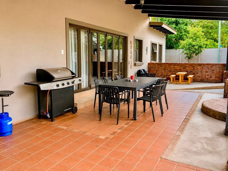Covered outdoor patio featuring tiled flooring, exposed timber beams, and direct access to the interior through large sliding glass doors.