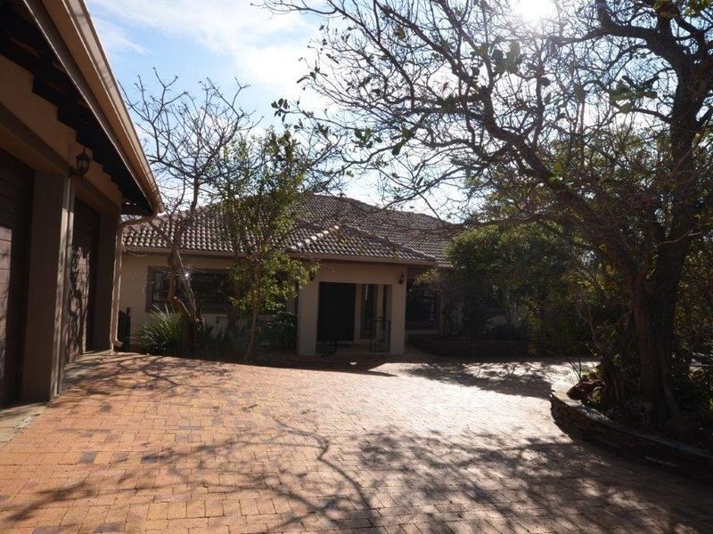 Front exterior view of the house featuring a brick paved driveway, covered entrance, and tiled roof structure.
