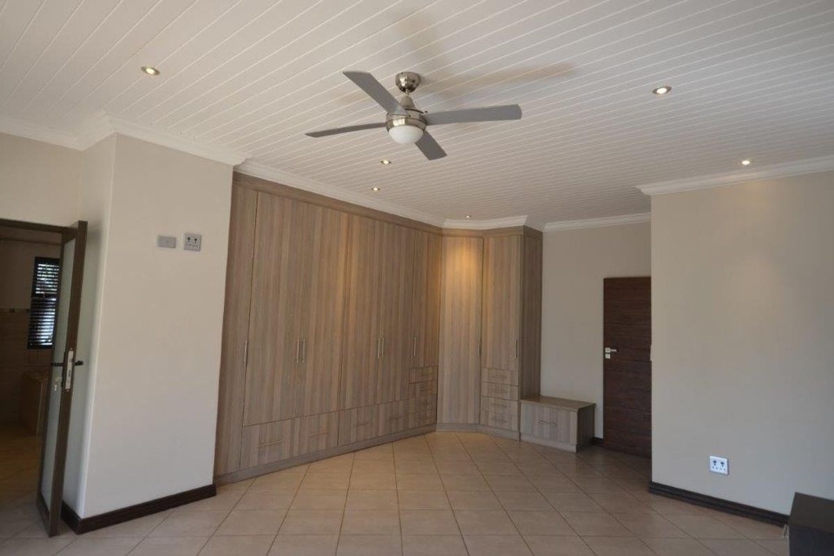 Spacious bedroom featuring extensive built-in cabinetry, tiled flooring, and a ceiling fan, offering a clean and neutral canvas for personalization.