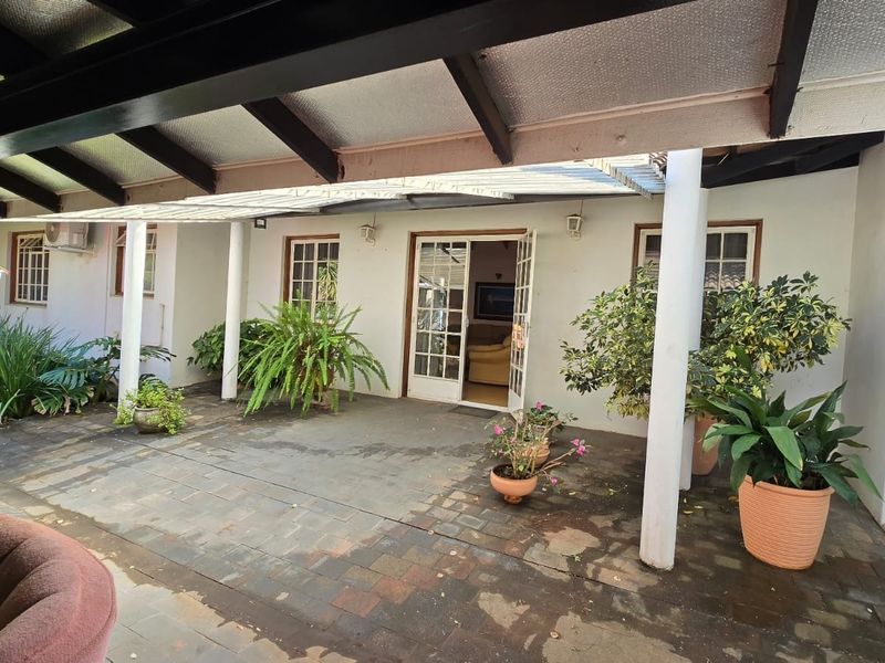 A covered outdoor patio area featuring paved flooring, support columns, and direct access to the interior through classic french doors.