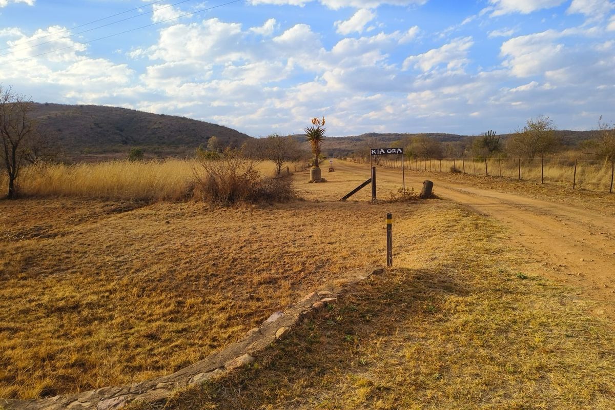 A view of the entrance to the vacant residential land, featuring a dirt road, wire fencing, and natural landscape.