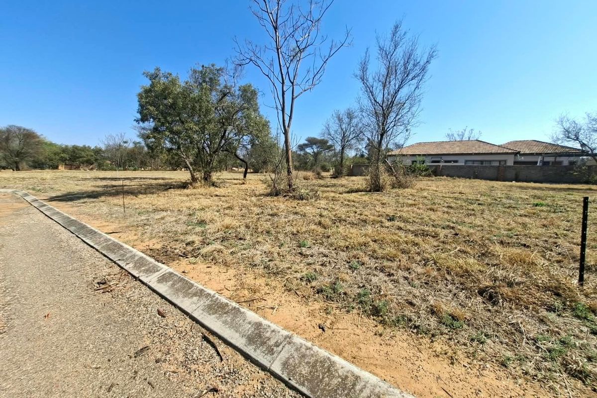 A vacant residential plot featuring a level landscape, concrete curbing, and an asphalt road frontage, ready for development.