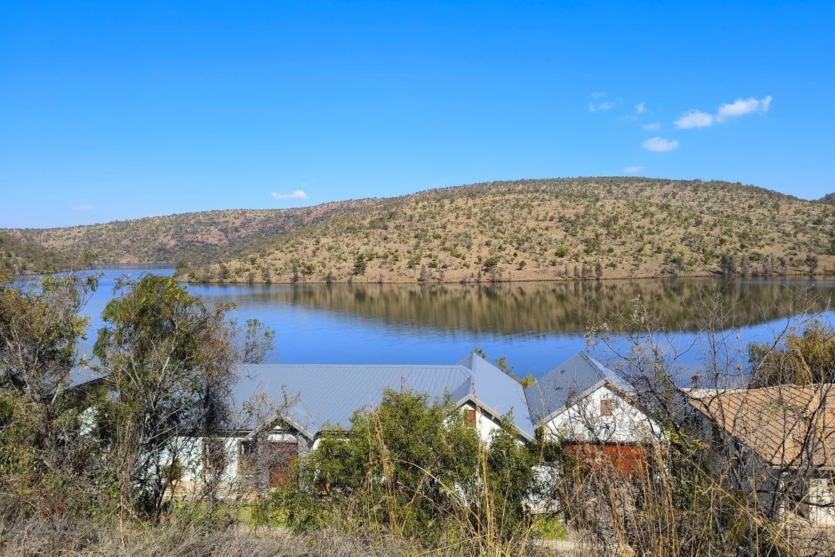 A scenic elevated view overlooking a tranquil lake surrounded by rolling hills and natural landscape.