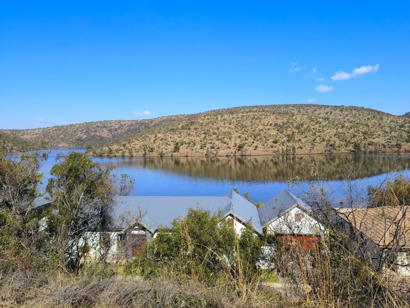 A scenic elevated view overlooking a tranquil lake surrounded by rolling hills and natural landscape.