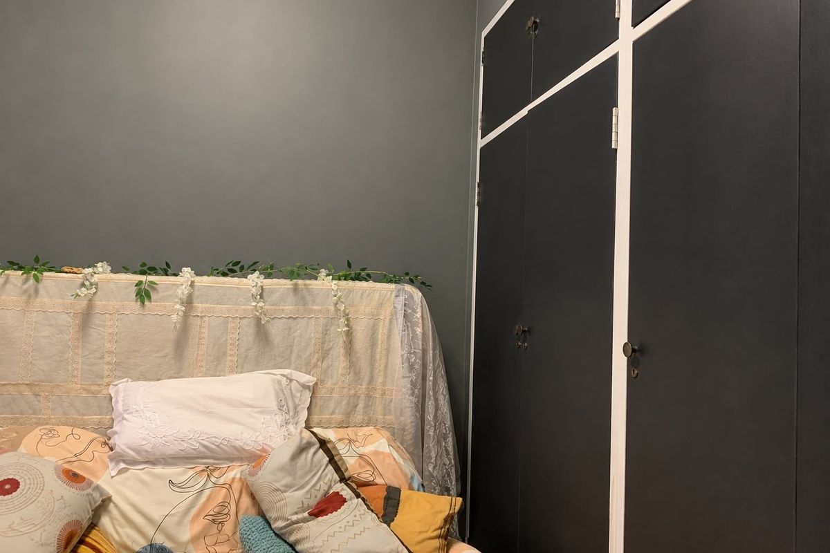 A bedroom featuring dark-painted built-in cupboards with contrasting white trim.