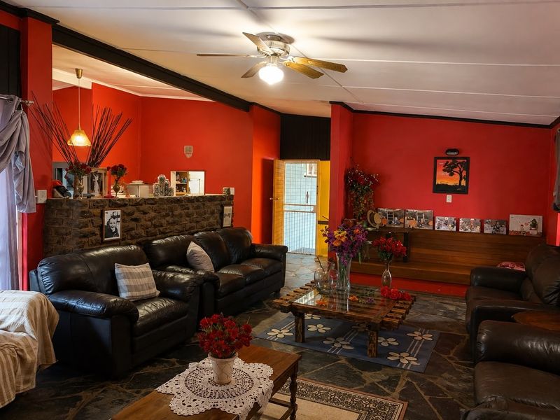 Spacious living room featuring natural stone flooring, a stone feature wall, and a ceiling fan, offering a rustic aesthetic with potential for modernization.