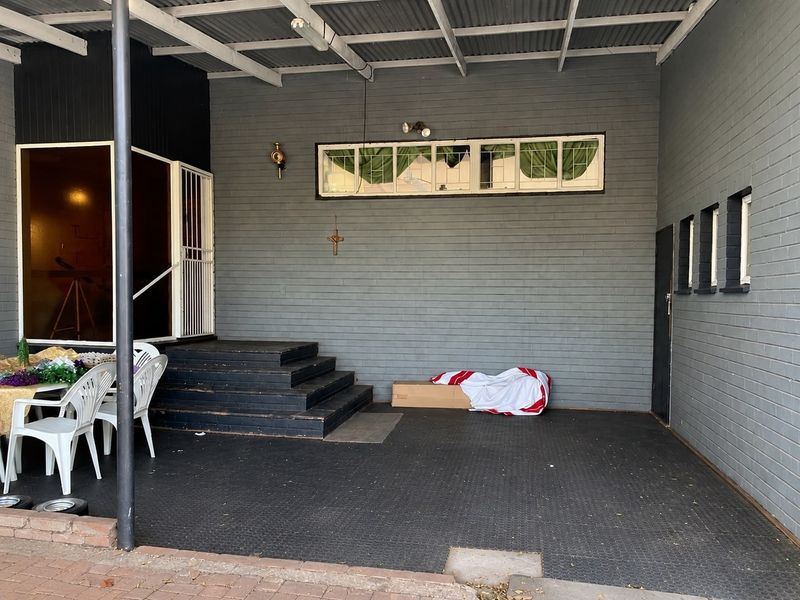 A covered outdoor patio area featuring painted brick walls, timber steps, and durable rubber flooring, providing a functional space for outdoor living.