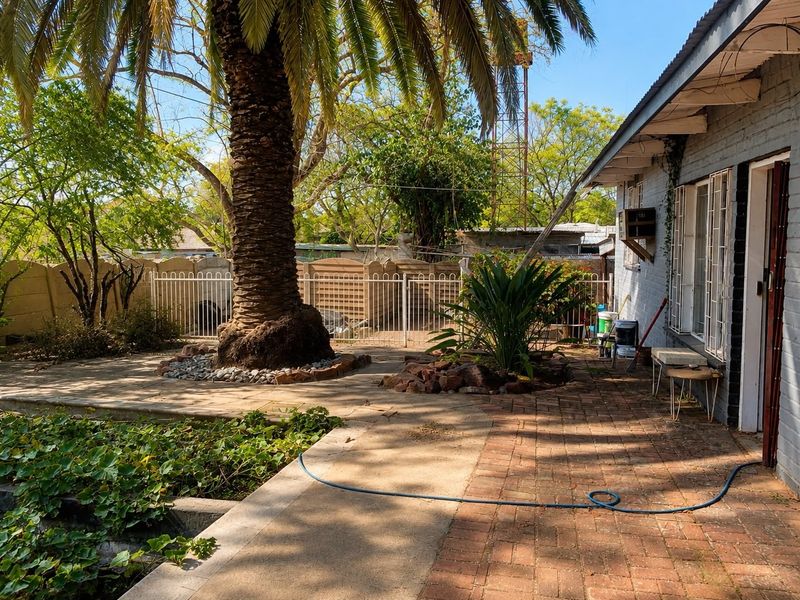 Rear garden area featuring brick paving, a concrete pathway, and established landscaping, providing a private outdoor space adjacent to the main dwelling.