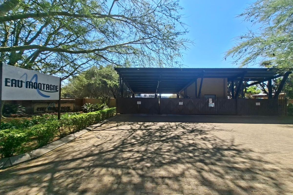The entrance to the Eau Montagne property features a paved driveway, secure gated access, and a covered structure.
