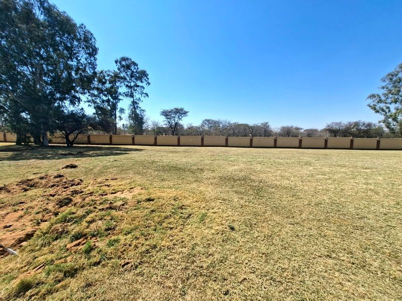 A spacious, level residential plot featuring a well-defined perimeter wall and mature trees, offering a clear canvas for future development.
