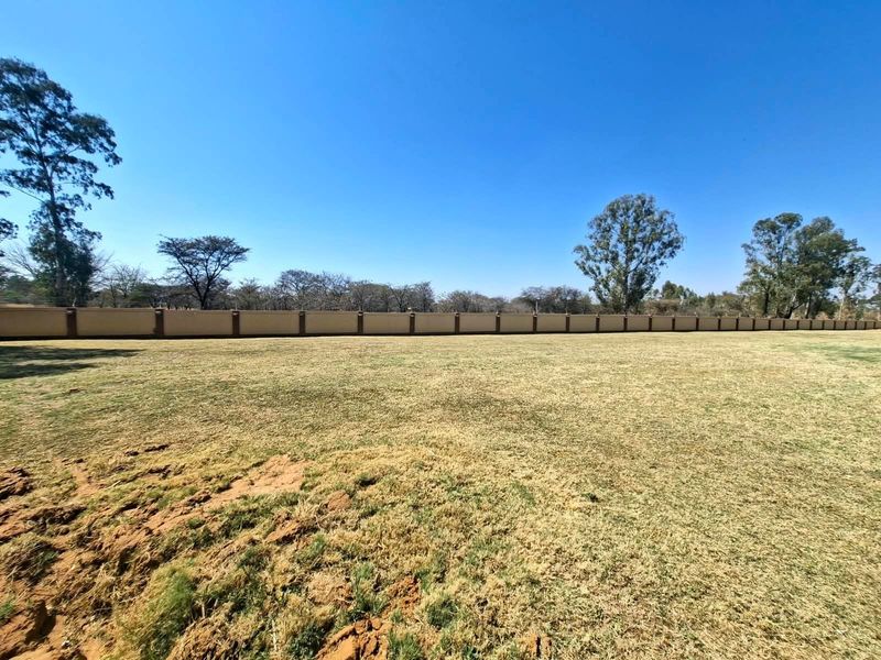 A spacious, level residential plot featuring a well-defined perimeter wall with integrated electric fencing, offering a clear canvas for future development.