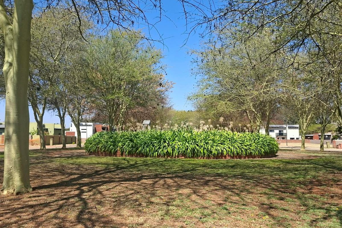 A well-maintained residential garden area featuring mature trees and a central circular landscaped planter bed.